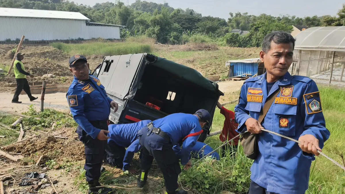 Sigap : Petugas Damkarla Gresik saat melakukan evakuasi Mobil Pick Up yang terperosok di area pekarangan berpagar di Jalan Mayjend Sungkono. (Ist/Radar Gresik) 
