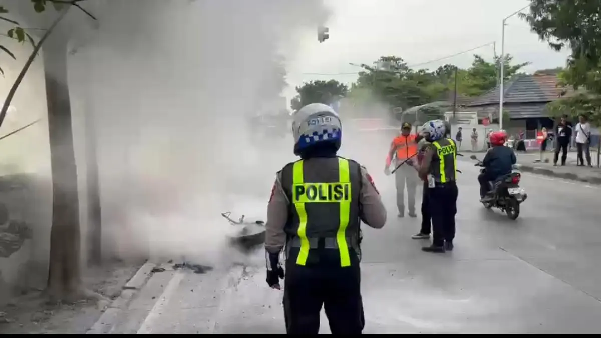 Pemadaman : Anggota Satlantas Polres Gresik saat memadamkan sepeda motor sport yang terbakar di Jalan Raya sekitar terminal Bunder, Gresik. (Ist/Radar Gresik) 