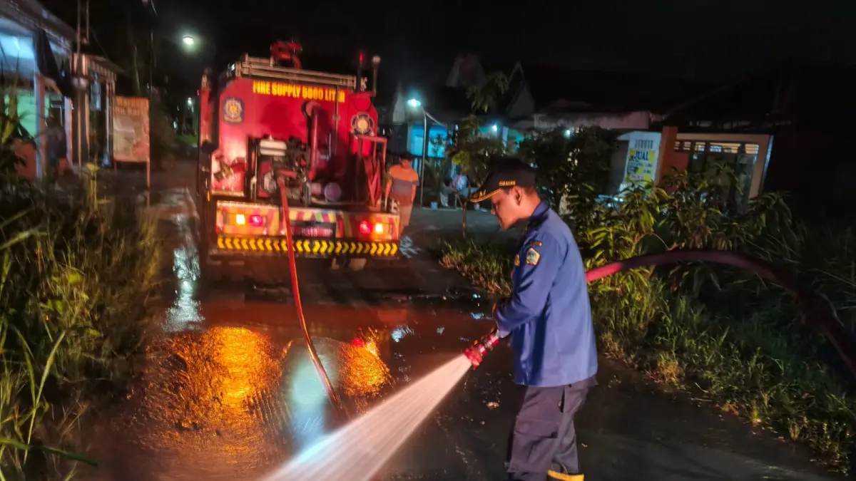 Disemprot : Petugas Damkar Gresik saat melakukan penyemprotan Jalan licin akibat ceceran tanah proyek di Desa Hendrosari, Kecamatan Menganti, Gresik.