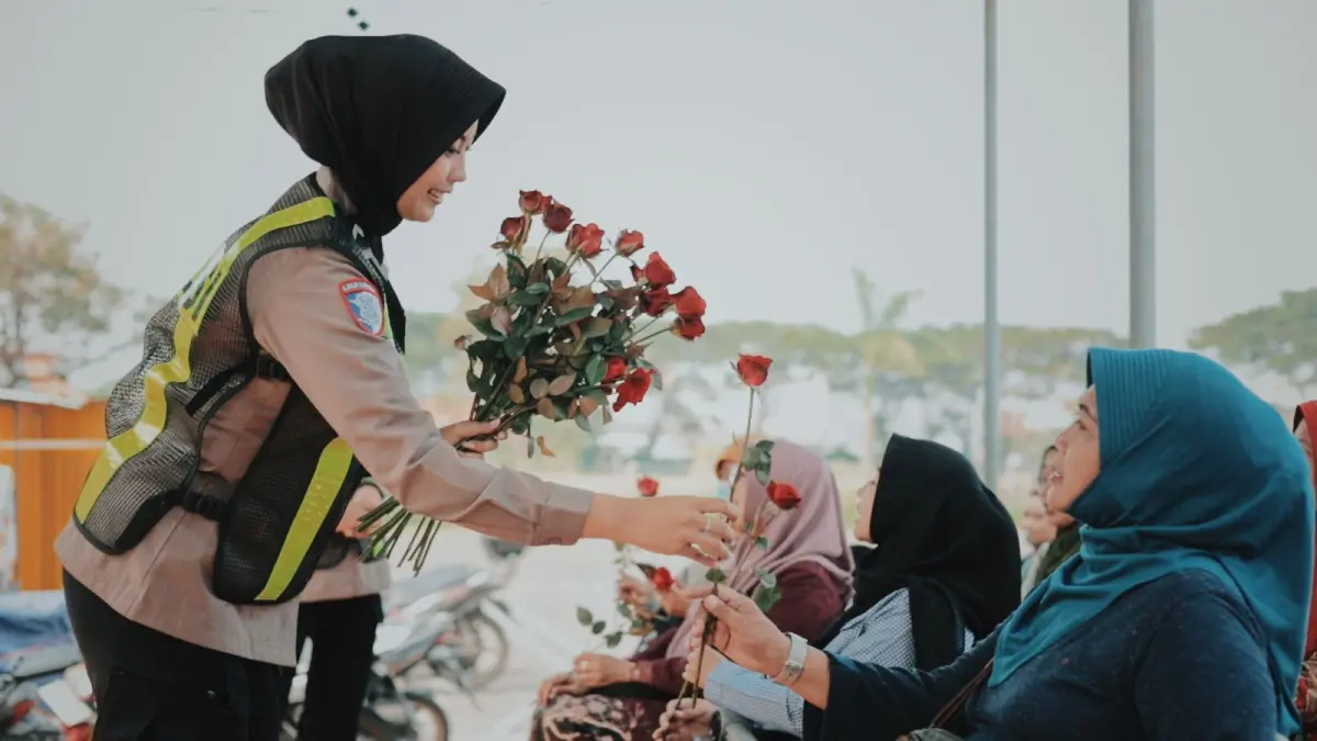 Kartini : Srikandi Satlantas Polres Gresik saat membagikan bunga serta memberikan edukasi simpatik dalam layanan SIM Keliling di kawasan PPS, Kecamatan Manyar, Gresik. (Yudhi/Radar Gresik) 