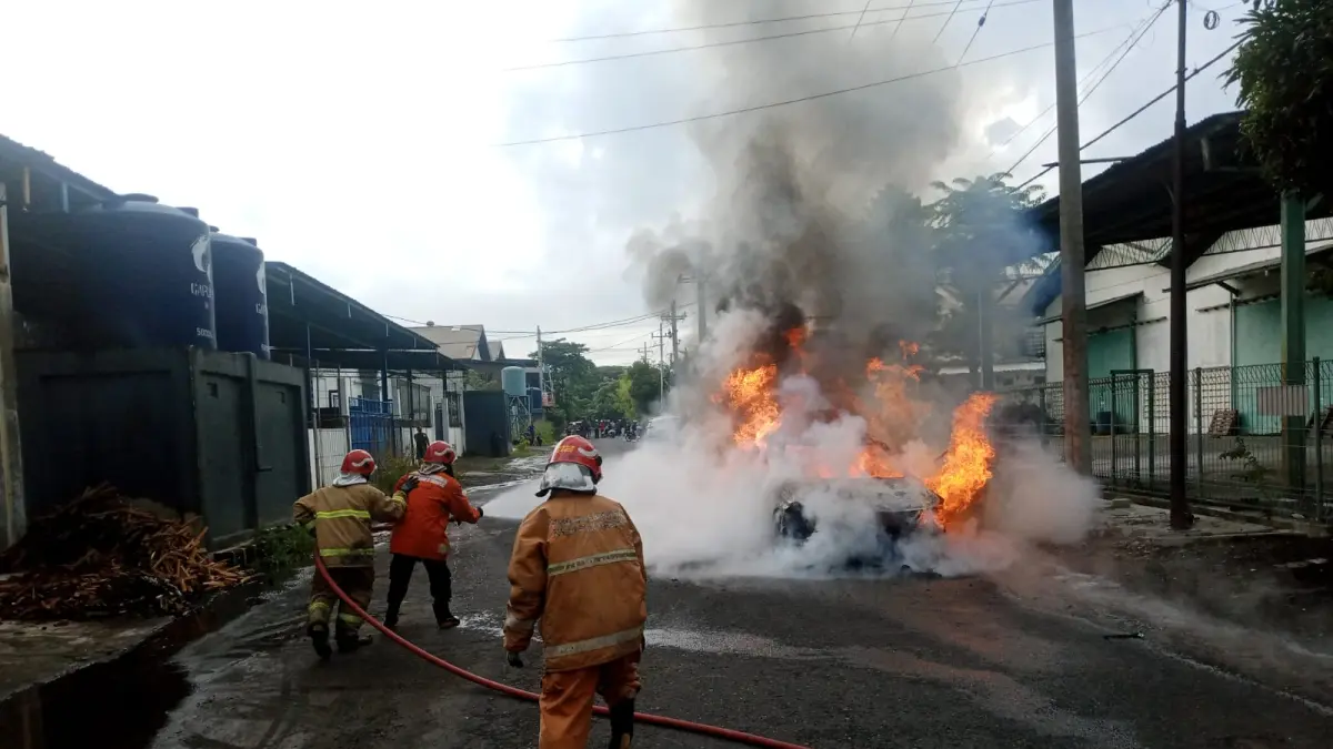 Pemadaman: Petugas Damkarla Gresik saat berjibaku memadamkan kobaran api yang menghanguskan sebuah mobil listrik di Jalan Mayjen Sungkono, Kebomas. (Ist/Radar Gresik) 