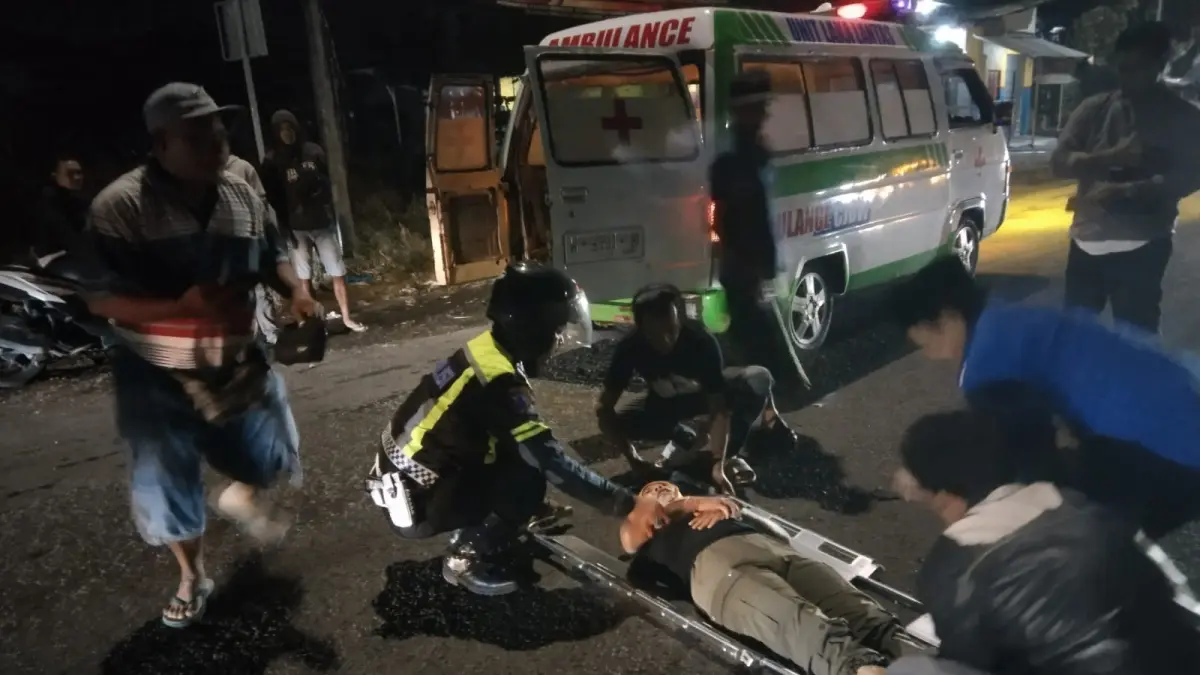 Beri Pertolongan : Anggota Polisi saat melakukan evakuasi korban kecelakaan lalu lintas di Jalan Raya Tenaru untuk segera dilarikan ke RS Anwar Medika guna penanganan medis. (Yudhi/Radar Gresik) 