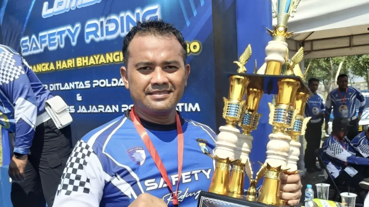 JUARA SAFETY RIDING: Personel Satlantas Polres Gresik, Aiptu Bambang Kurniawan, saat berpose bersama piala kejuaraan usai dinobatkan sebagai Juara 1 Lomba Safety Riding Hari Bhayangkara ke-80. (Ist/Radar Gresik) 