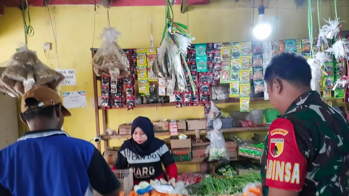 Pendekatan: Babinsa Koramil Manyar, Serda Choiril A, saat melakukan pendekatan humanis melalui dialog santai bersama pedagang di Pasar Desa Manyar Sidomukti, Gresik. (Ist/Radar Gresik) 