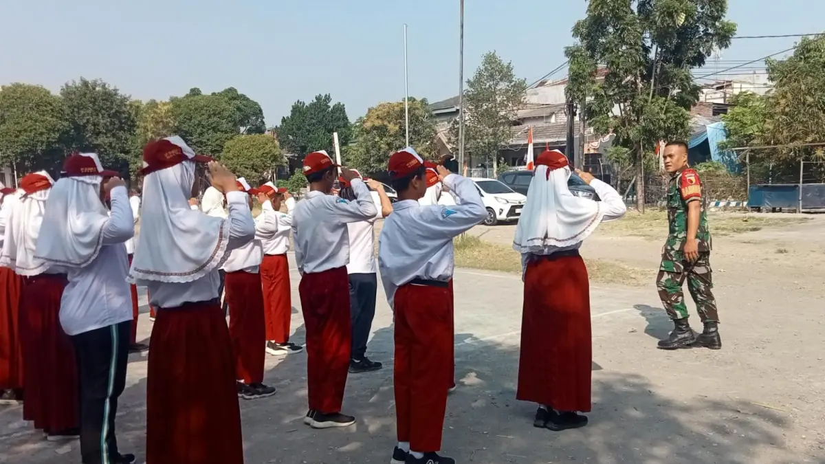 DISIPLIN: Babinsa Desa Betiting Serda Arizky Lugas Yuwono dari Koramil 0817/08 Cerme saat menggembleng latihan PBB dasar guna menanamkan karakter disiplin sejak dini kepada siswa-siswi SDN 56 Gresik. (Foto: DOK/RADAR GRESIK)