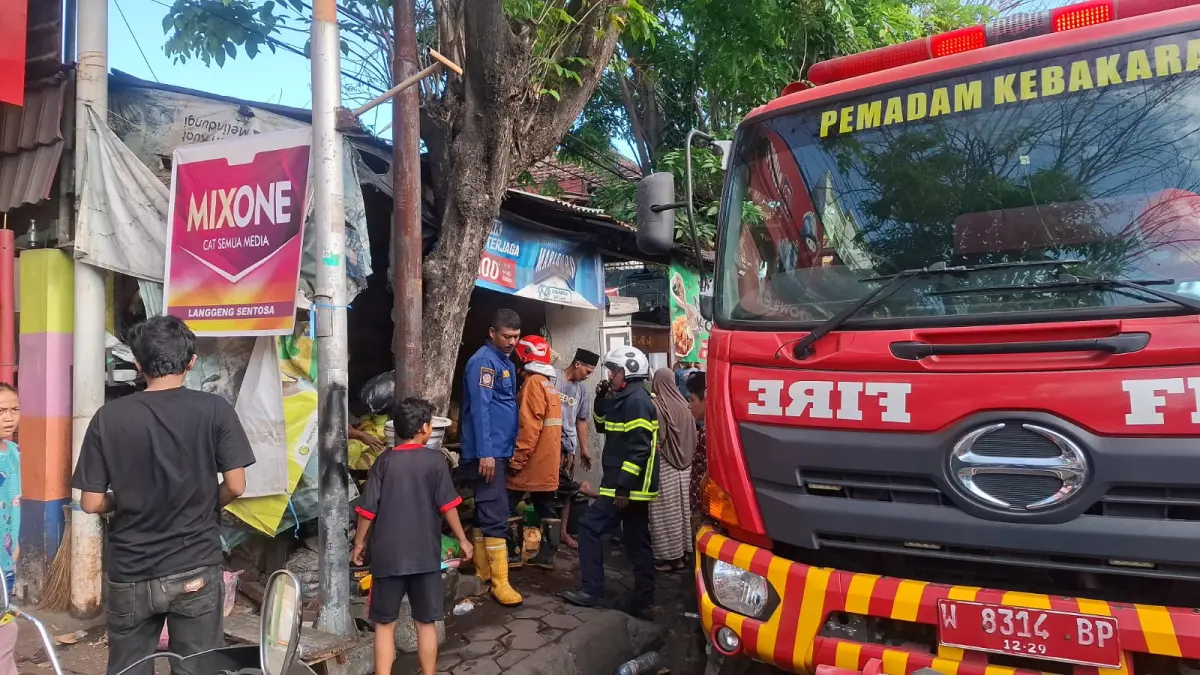 PEMBASAHAN : Petugas Damkar Gresik saat melakukan penyemprotan menggunakan selang air di sebuah Ruko terbakar di Jalan Usman Sadar Gresik. (Foto : Ist/Radar Gresik) 