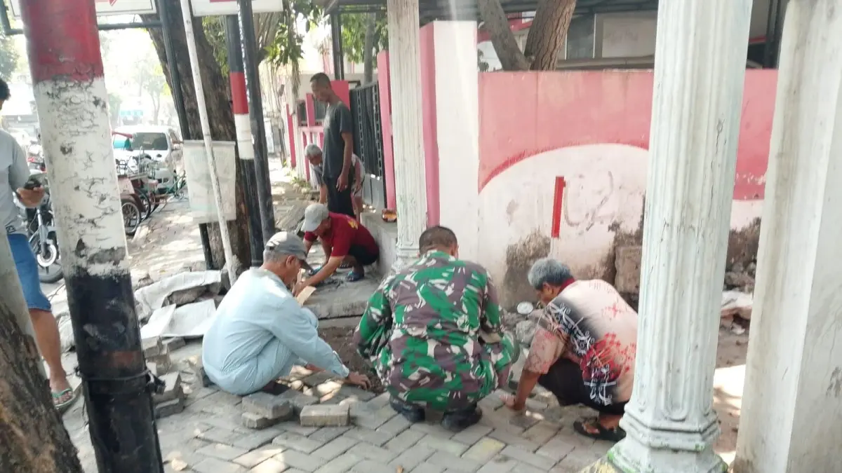 Personel Babinsa Koramil 0817/05 Kota Gresik saat bahu-membahu bersama warga Kelurahan Sukorame membersihkan tumpukan sampah di saluran air sebagai langkah preventif mencegah sarang nyamuk penyebab DBD. (Foto : Fajar/Radar Gresik) 