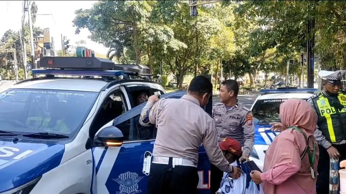 DIANTAR PULANG : Anggota Satlantas Polres Gresik saat mengantarkan Siswa SD yang tersesat pulang ke rumahnya. (Foto : Ist/Radar Gresik) 