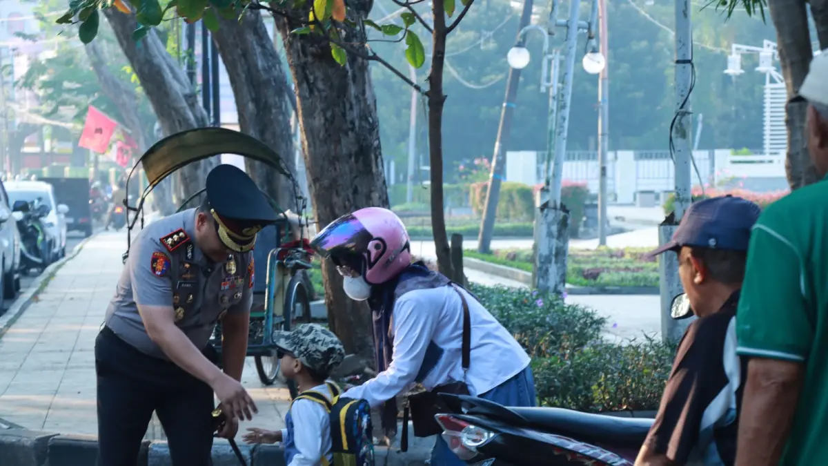 TURUN KE JALAN : Kapolres Gresik AKBP Ramadhan Nasution turun ke jalan mengatur lalulintas agar jalak aman dan menyapa siswa hari pertama masuk ke sekolah di Gresik. (Foto : Ist/Radar Gresik) 