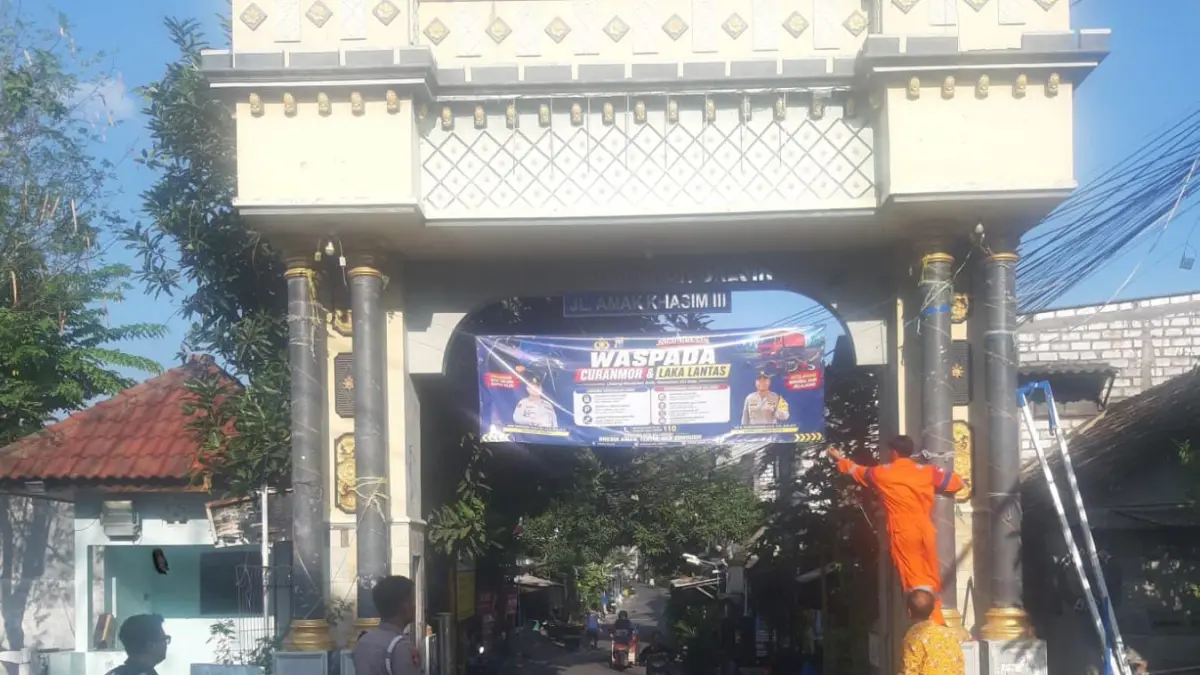 HIMBAUAN : Anggota Polsek Gresik Kota dibantu warga saat memasang spanduk himbauan terkait pencegahan tindakan Kriminalitas dan kecelakan lalu lintas di Desa Sidorukun, Kecamatan Gresik. (Foto : Ist/Radar Gresik) 
