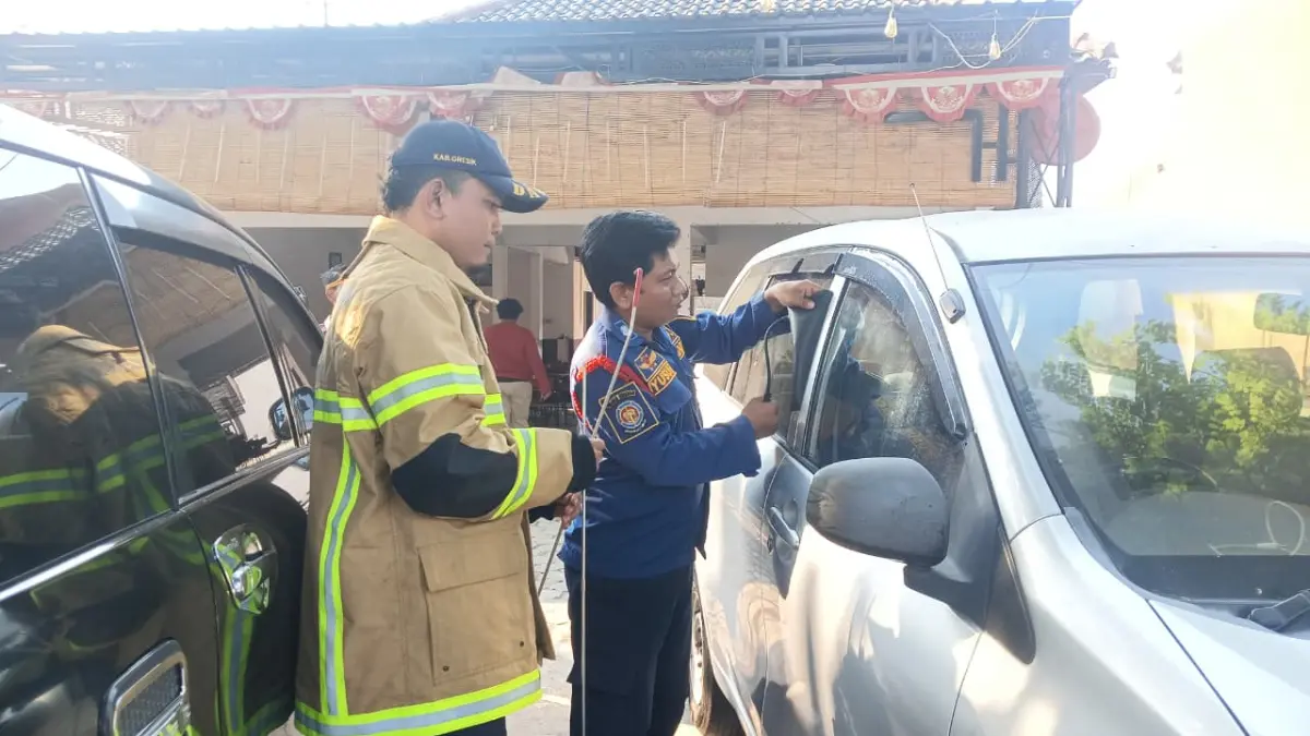 MEMBANTU : Petugas Damkarla Gresik saat melakukan penyelamatan kunci mobil milik warga yang tertinggal di dalam kendaraan di Jalan Raya Benjeng, Desa Bulurejo, Kecamatan Benjeng, Gresik. (Foto : Ist/Radar Gresik) 