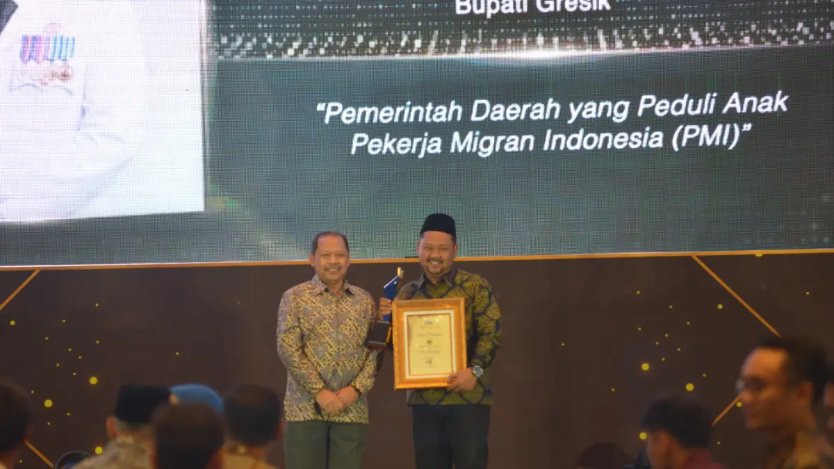 Bupati Gresik H. Fandi Akhmad Yani, S.E., M.MB. saat menerima penghargaan dari Direktur Radar Surabaya Lilik Widyantoro. (Dok/Radar Gresik)