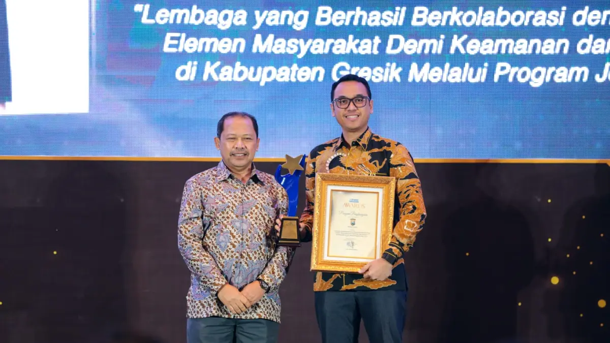 Wakapolres Gresik Kompol Shabda Purusha Putra (kanan) menerima penghargaan yang diserahkan Direktur Radar Surabaya, Lilik Widiantoro. (Andy Satria/Radar Surabaya)