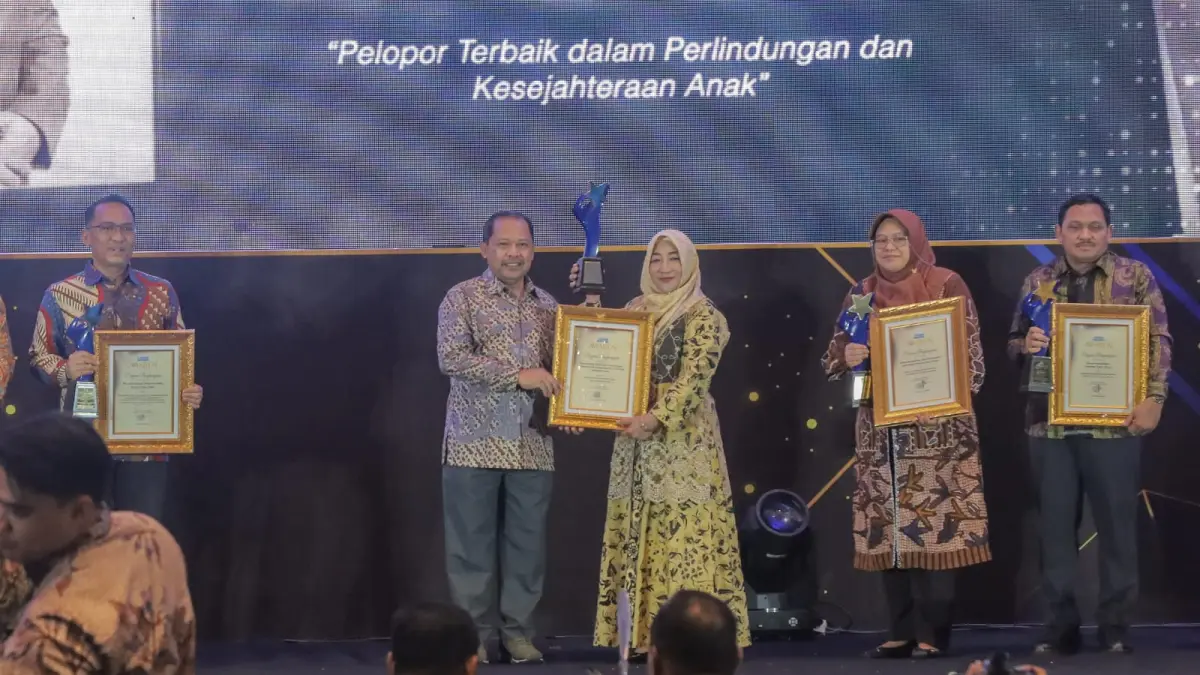 Kepala Dinas KBPPPA Gresik, dr. Titik Ernawati, M.H. menerima penghargaan secara langsung dari Direktur Radar Surabaya Lilik Widyantoro. (Foto : Dok/Radar Surabaya) 