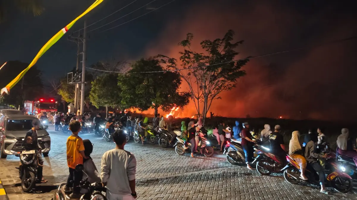 PEMADAMAN : Puluhan warga saat melihat petugas Damkar saat melakukan pemadaman kebakaran lahan kosong fekat permukiman di PPS II, Desa Banjarsari, Kecamatan Manyar Gresik. (Foto : Yudhi/Radar Gresik) 