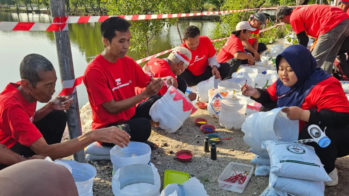 KREASI : Selain membersihkan aliran sungai dan jalan desa, sejumlah warga Dusun Banyutami juga menyulap botol bekas air mineral menjadi pot bunga yang cantik. Foto : Firman / Radar Gresik.