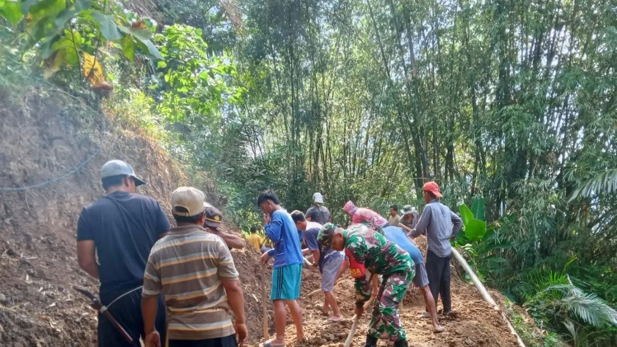 BERSIHKAN : Babinsa Sangkapura bersama warga gotong royong bersihkan jalan tertimbun longsor. (Foto : Ist/Radar Gresik) 