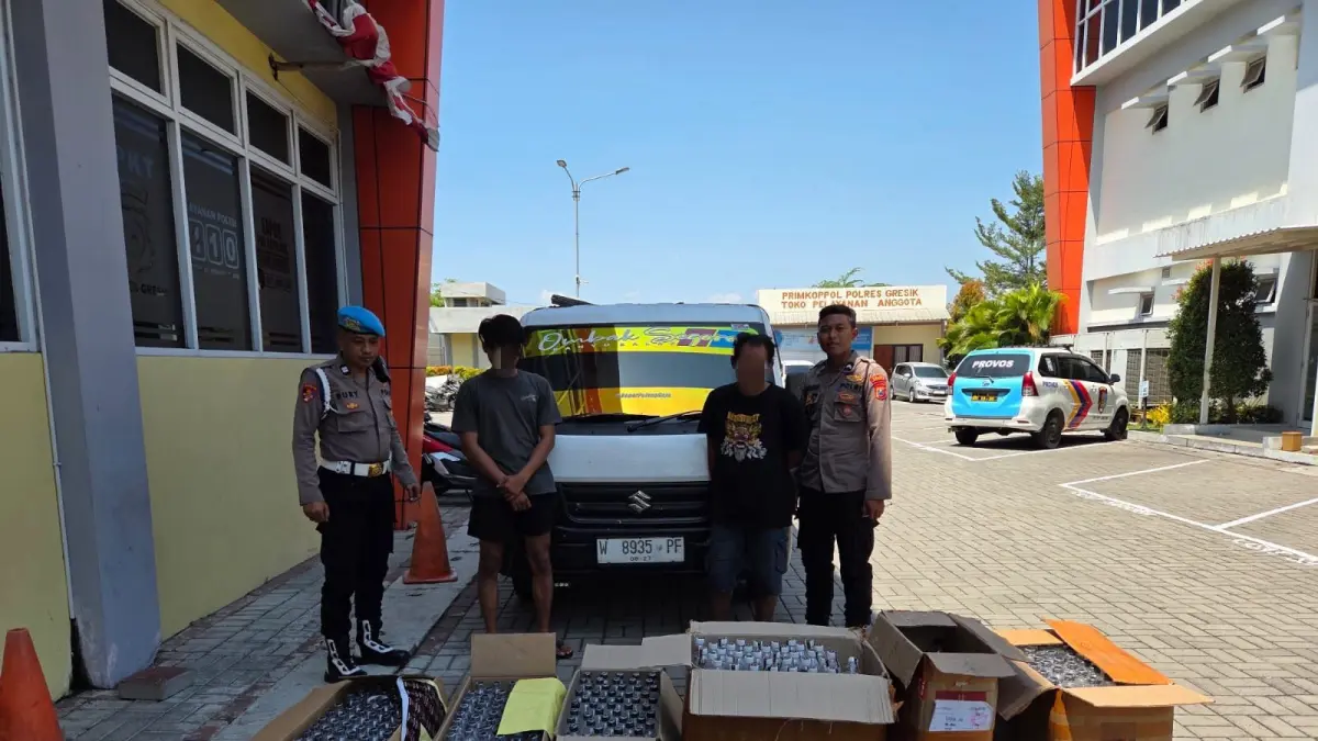 DIAMANKAN : Anggota Satresnarkoba Polres Gresik saat mengamankan 439 botol arak Bali dan dua pemiliknya di Mapolres Gresik. (Foto : Ist/Radar Gresik) 