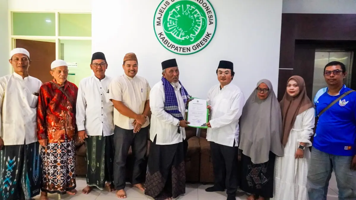 MEMELUK ISLAM: Ketua Umum MUI Kabupaten Gresik KH. Ainur Rofiq Thoyyib (tengah) menyerahkan surat keterangan ikrar mualaf kepada Li Qun (31), pekerja asal China yang bekerja di kawasan JIIPE Manyar. (Foto : Ist/Radar Gresik) 