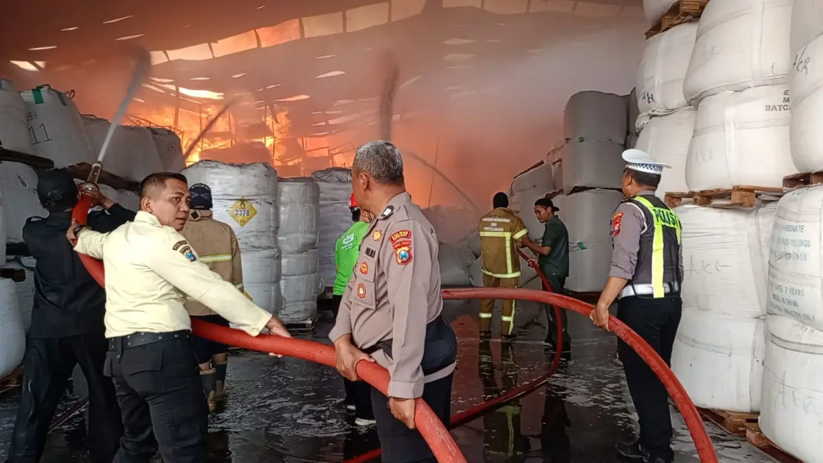 BANTU MEMADAMKAN: Anggota Kapolsek Driyorejo Kompol Gatot bersama anggota ikut menbantu memadamkan kebakaran gudang penyimpanan bahan baku milik PT Wings Surya. (Foto : Ist/Radar Gresik) 