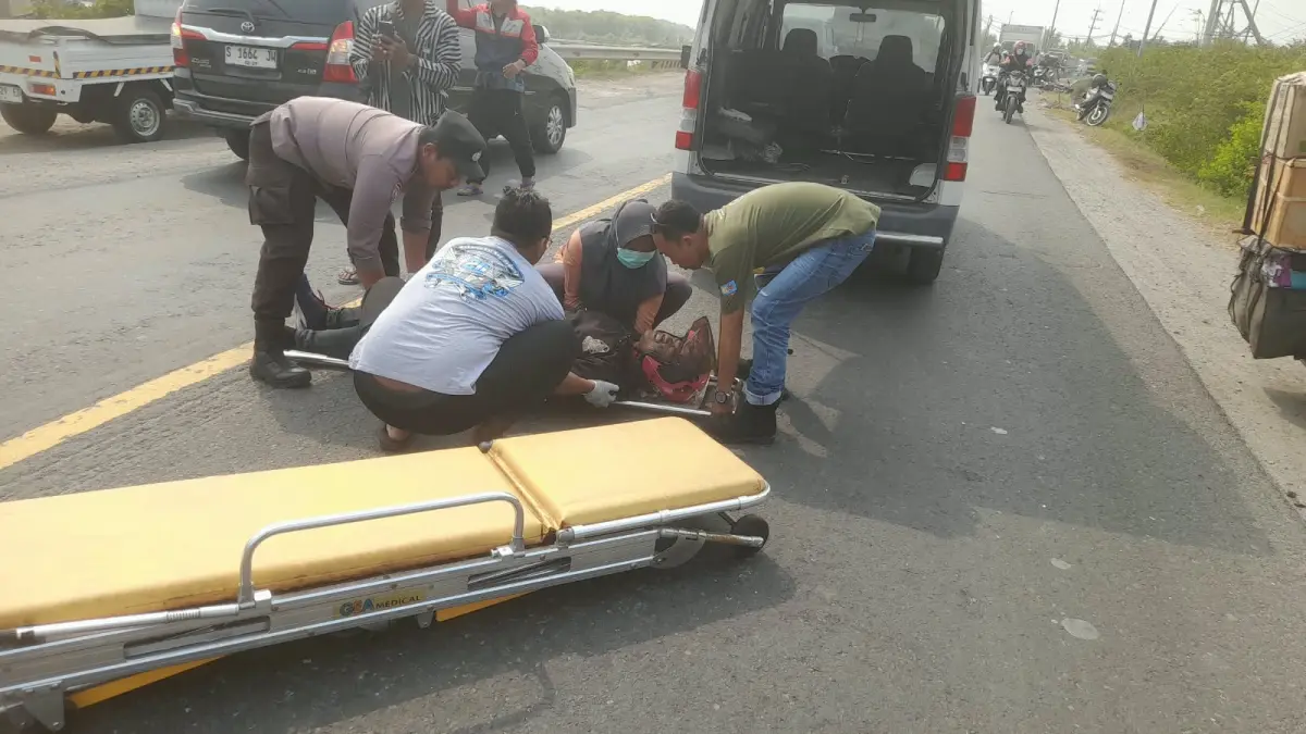 EVAKUASI : Anggota Polsek Manyar dibantu tim medis saat melakukan evakuasi korban kecelakan di Jalan Raya Daendles, Desa Banyutami, Kecamatan Manyar, Gresik. (Foto : Ist/Radar Gresik) 