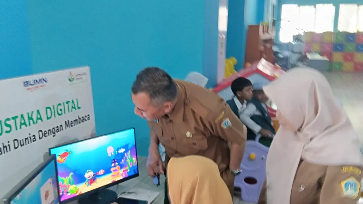 MEWARNAI: Kepala Dispussip Kabupaten Gresik Budi Raharjo saat mendampingi anak-anak mewarnai di fasilitas Aquarium Digital. (Foto : Fajar/Radar Gresik)