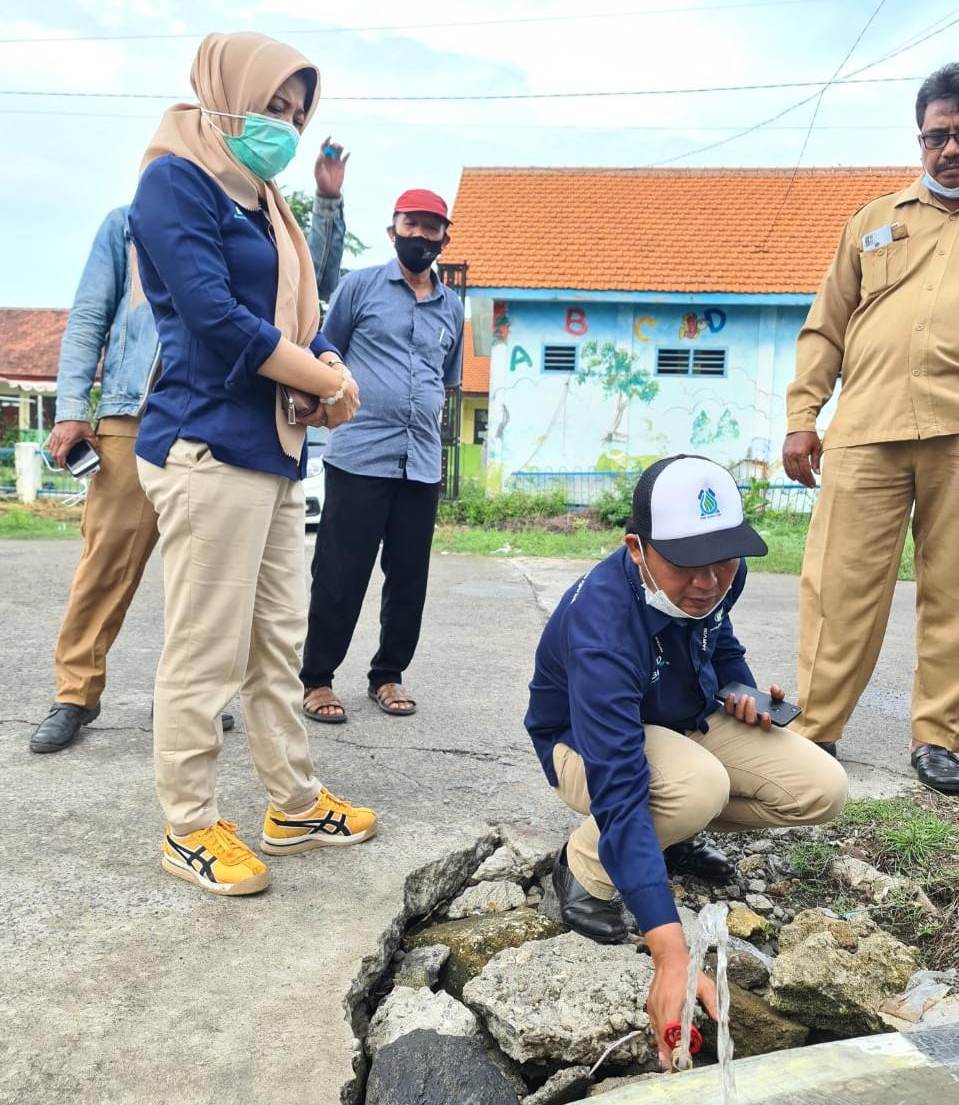 Kepala PDAM Giri Tirta Cabang Cerme, Kasmanto memutar kran air didepan kantor balai desa Semampir  disaksikan Dirut PDAM Giri Tirta Gresik dan Kades Semampir, Achmad Sahid. (Firman/Radar Gresik)