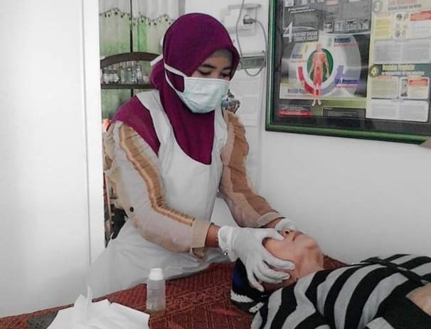 Telaten : Nurul Hidayati saat menangani pasien di klinik tradisionalnya. (Riri/Radar Gresik)