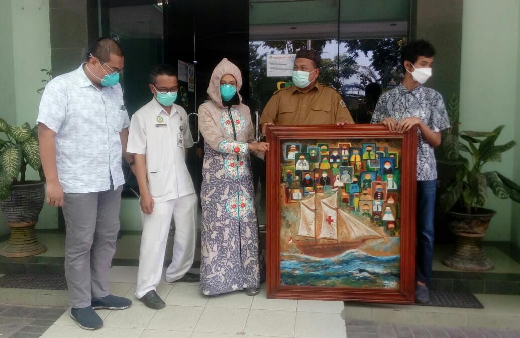 LUKISAN: Salah satu pelukis yang memberikan lukisan kepada RSUD Ibnu Sina Kabupaten Gresik. (FAJAR/RADAR GRESIK)