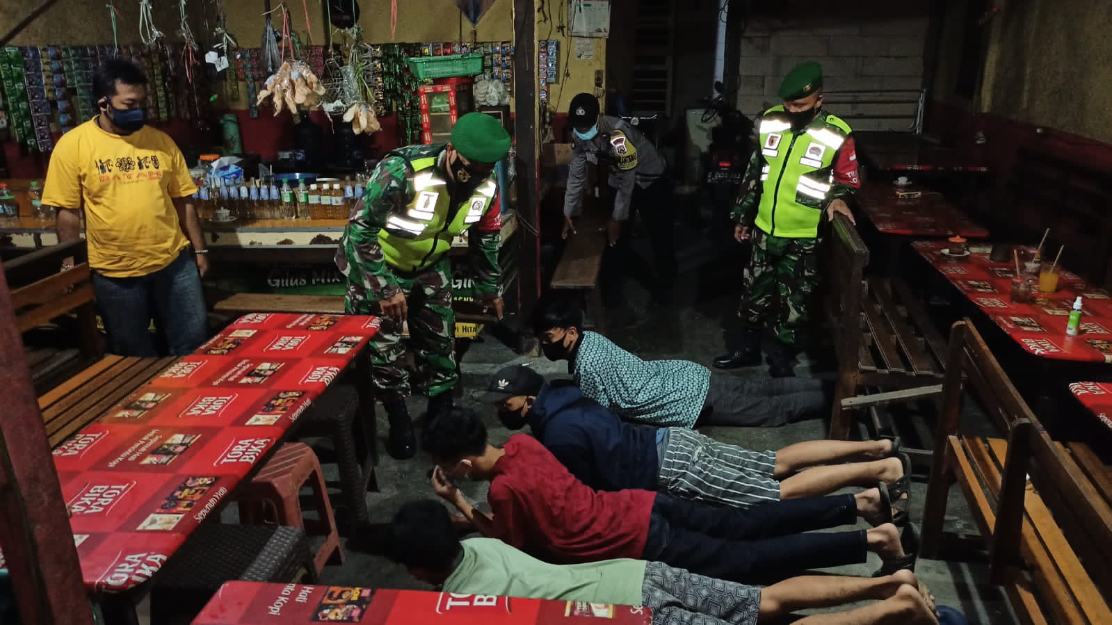 DIBUBARKAN: Petugas Gabungan anggota Polsek Manyar dan Koramil Manyar saat membubarkan muda mudi yang asik berkerumun di dalam warung kopi yang dimatikan lampunya. (Yudhi/Radar Gresik )
