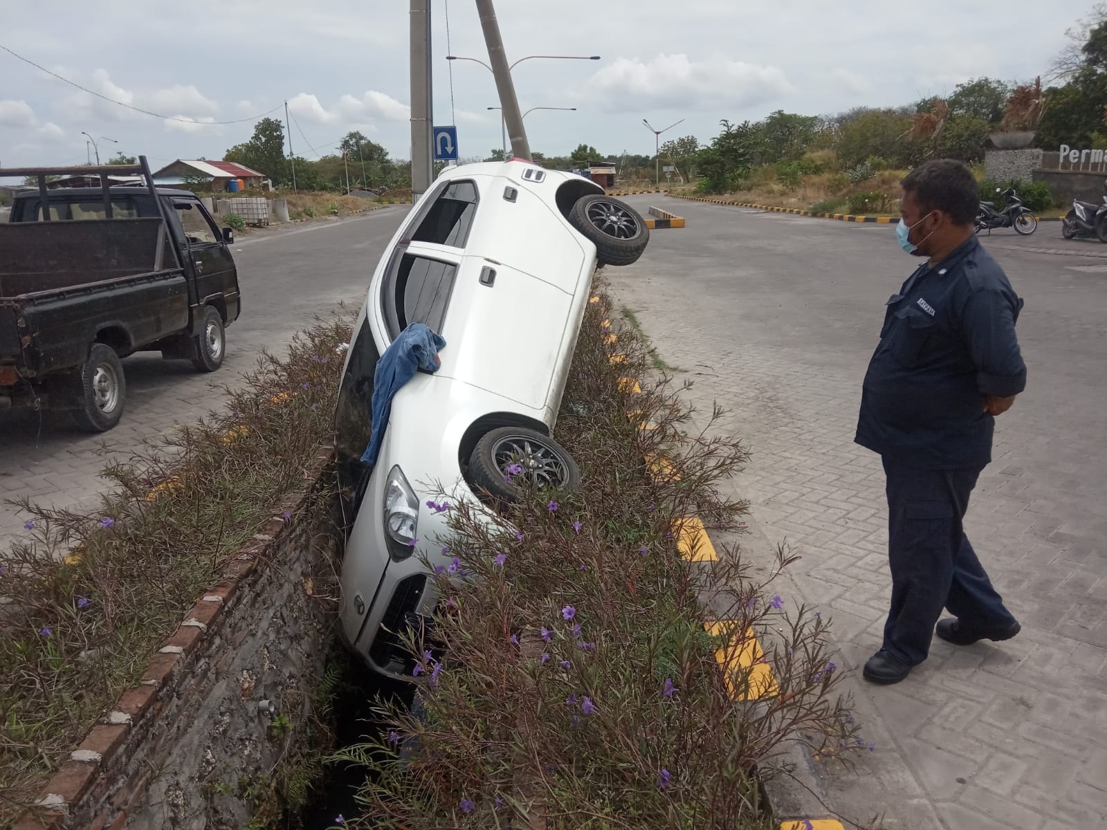 MASUK PARIT: Mobil Daihatsu Ayla warna putih nopol W 1526 AQ masuk kedalam parit di jalan Raya Pondok Permata Suci (PPS 2) depan Perum Optima, Desa Banjarsari, Kecamatan Manyar.  (Yudhi/Radar Gresik)