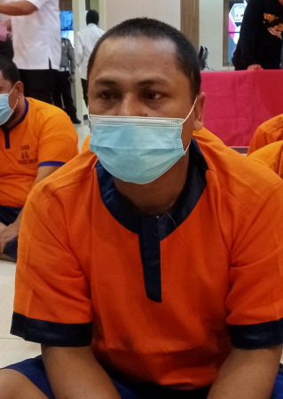 MENUNDUK: Abdullah Musyafak pelaku pembunuhan janda saat diamankan di Mapolres Gresik. (Yudhi/Radar Gresik )