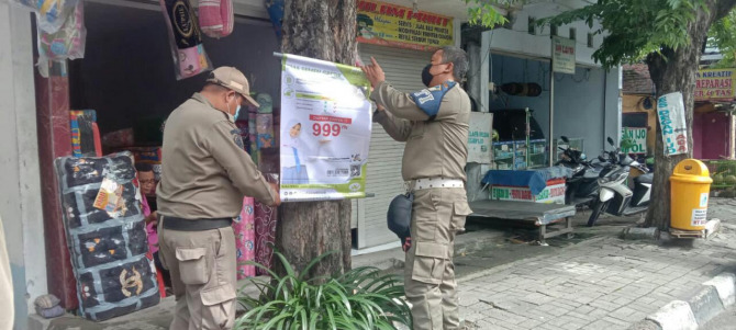 DITERTIBKAN: Petugas Satpol PP Gresik melakukan penertiban spanduk yang tidak mempunyai izin. (Dok/Radar Gresik)