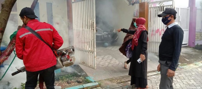 FOGGING : Petugas puskesmas dan warga melakukan fogging ke rumah warga sekitarnya. (Dok/Radar Gresik)