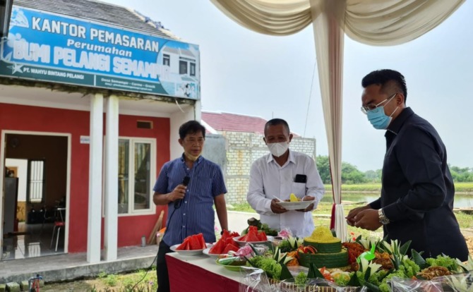 EKSPANSI: CEO PT Keluarga Sejahtera Grup (KSG) Thoriq Majiddanor (kanan) memberikan potongan tumpeng kepada kepala desa Semampir M. Syahid saat acara launching perumahan Bumi Pelangi Semampir by Golden East. (FIRMAN/RADAR GRESIK)
