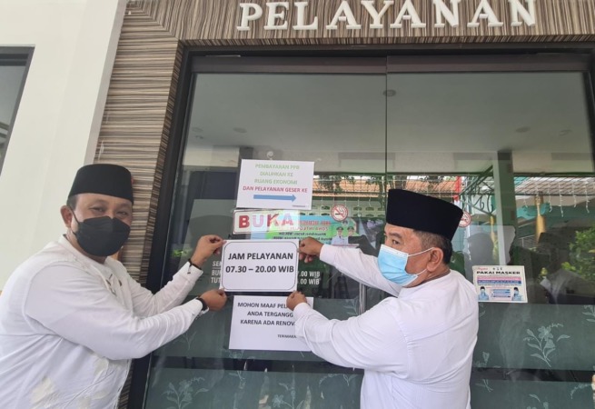 TAMBAH JAM: Camat Gresik Agung Endro menempelkan pengumuman perpanjangan pelayanan hingga pukul 20.00. (Dok/Radar Gresik)