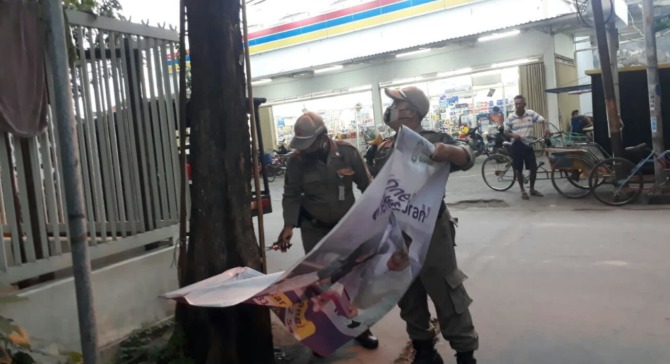 PENERTIBAN: Anggota Satpol PP Gresik menertibkan puluhan spanduk yang tidak mempunyai izin. (DOK/RADAR GRESIK)