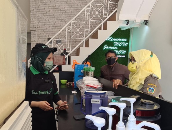 BERI TEGURAN: Petugas trantib Kecamatan Gresik Puji Rahayu memberikan teguran kepada pegawai café minuman di alun-alun Gresik yang melayani dine in dan beroprasi tanpa penutup