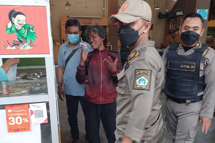 MENGAMUK: Orang Dengan Gangguan Jiwa (ODGJ) mengamuk dan merusak ATM nurut saat digelandang petugas masuk mobil dinas sosial. (Fir/Radar Gresik)