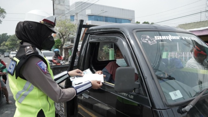 BAGIKAN MASKER: Anggota Polwan Satlantas Polres Gresik saat bagikan masker ke pengendara di beberapa titik jalan protokol di Gresik.  (Ist/Radar Gresik)