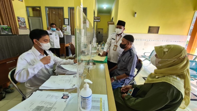 Beri Penjelasan : Petugas Kemenag Gresik memberikan penjelasan kepada CJH yang melihat perubahan estimasi keberangkatan ke Tanah Suci. (Ist./Radar Gresik)