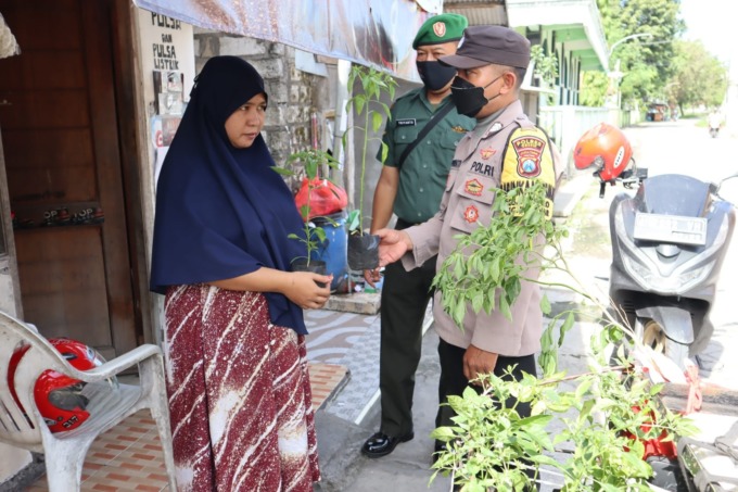 BIBIT CABAI: Anggota Bhabinkamtibmas Polsek Manyar dan Babinsa Koramil Manyar saat memberikan bibit cabai rawit ke warga. (Ist./Radar Gresik)