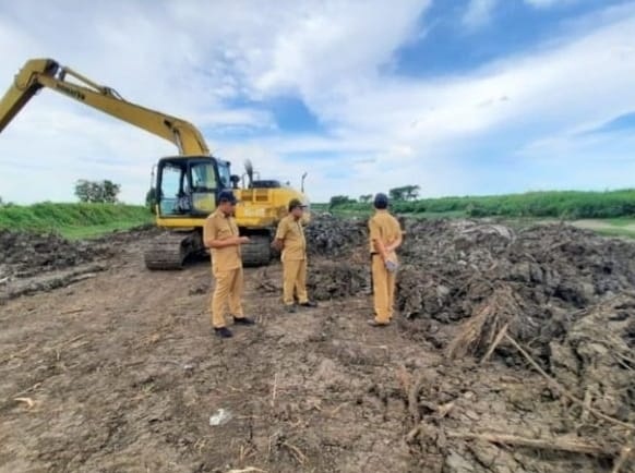 DIKEBUT: Pegawai Dinas Pekerjaan Umum dan Tata Ruang (DPUTR) memantau proses pengerukan Kali Lamong di wilayah Kecamatan Cerme. (Ist./Radar Gresik)