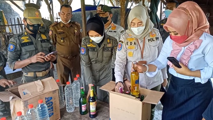 DIRAZIA: Petugas gabungan melakukan razia warung dan rumah menemukan ratusan miras dan mengamankan tiga pramusaji. (Ist./Radar Gresik)