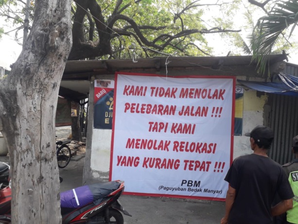 TOLAK RELOKASI: Pedagang di Manyar memasang banner penolakan relokasi di depan stannya. (Dok/Radar Gresik)