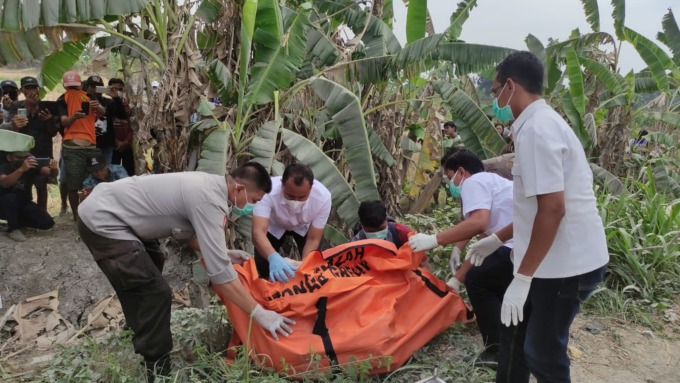 DIEVAKUASI : Anggota Satreskrim Polres Gresik dibantu petugas kesehatan dan warga saat mengevakuasi korban yang ditemukan di pinggir jalan di Desa Gluranploso, Kecamatan Benjeng.  (Yudhi/Radar Gresik)