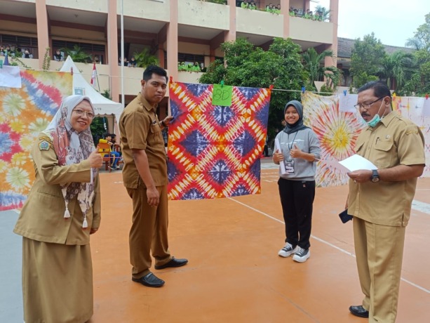 KREATIFITAS : Kepala UPT SMPN 1 Gresik Beri Avita Prasetya didampingi waka kesiswaan dan osis mengamati salah satu kreasi siswanya. (Riri)