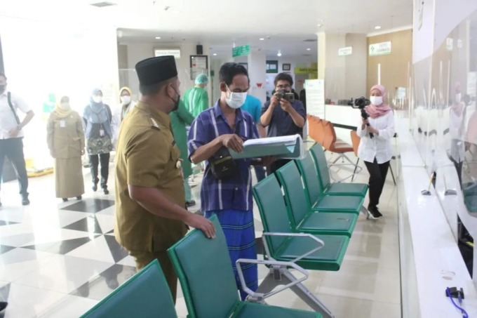 KEJAR TARGET: Bupati Gresik Fandi Akhmad Yani saat melihat data pasien yang akan mendaftarkan diri ke program UHC di Gresik. (Ist./Radar Gresik)