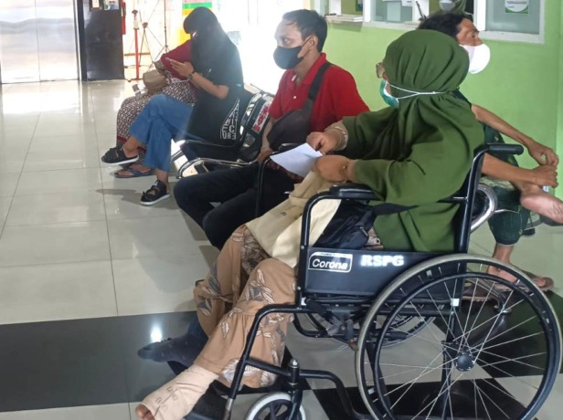 Masrupiah ditemani anaknya menunggu antrian pemeriksaan kesehatan. (Riri/Radar Gresik)