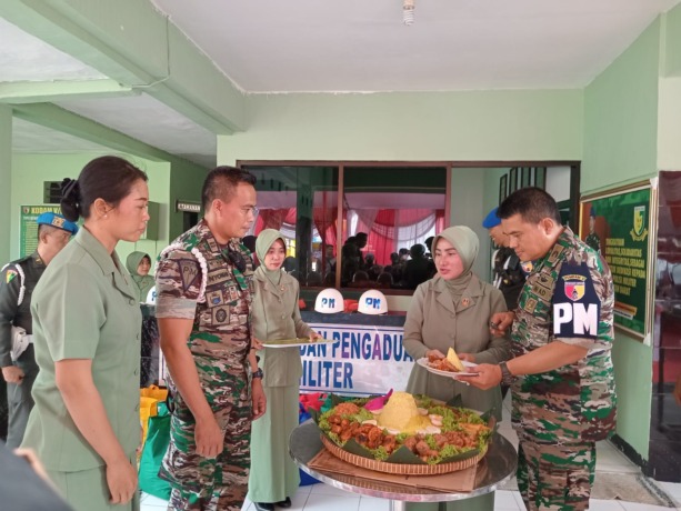 Seksama : Danpomdam V Brawijaya Kolonel Cpm Reza Muhammad H. Nasution memotong tumpeng dan memberikannya kepada Dansubdenpom Gresik Lettu Cpm I Nyoman Gde Budearta saat berkunjung ke Gresik. (Riri/Radar Gresik)